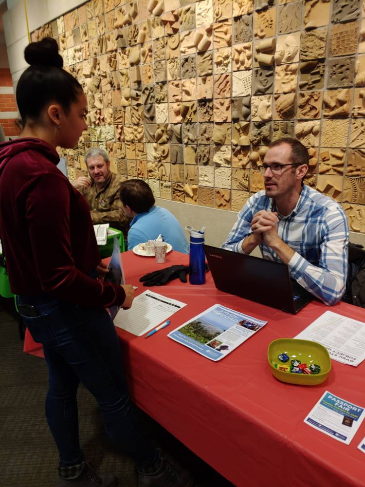 Professor Linford talking with a student at the Dominican Republic study abroad table